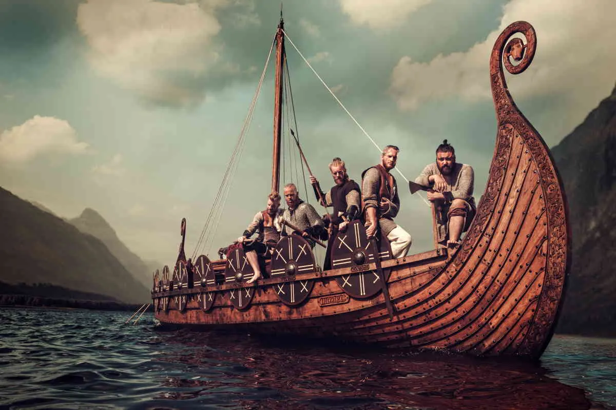 gruppo Vichinghi su barca sul Mare Drakkar con Le Montagne sullo Sfondo